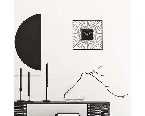 Dekorativ inredning med en fyrkantig väggklocka, ljus och en vas med en kvist