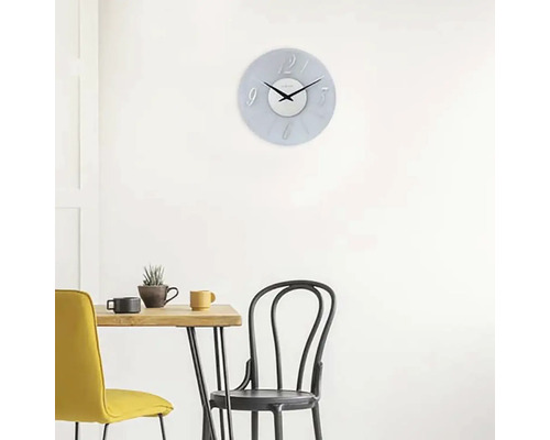 Scen med en väggklocka ovanför ett matbord med stolar