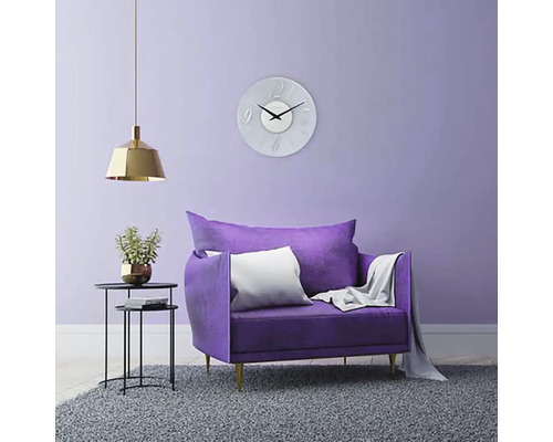 Vardagsrum med fåtölj, väggklocka, golvlampa och matta