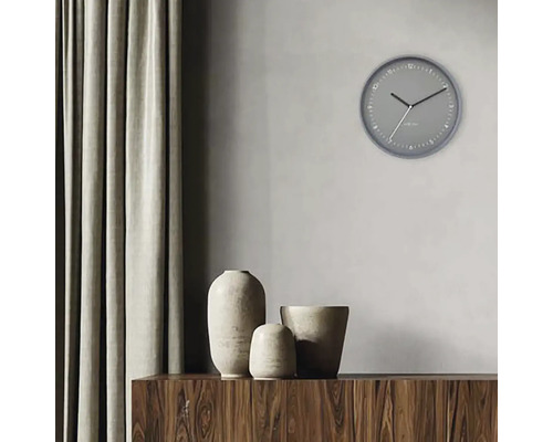 Scen med en grå väggklocka, tre vaser på ett träskåp och en gardin