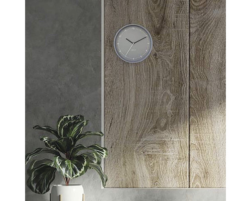 Bild med väggklocka, krukväxt och träpanel