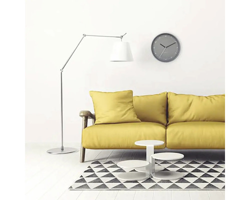 Vardagsrum med gul soffa, golvlampa, väggklocka och matta med geometriskt mönster