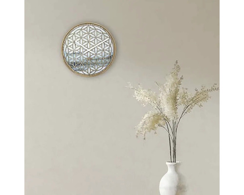 Dekorativ väggklocka med geometriskt mönster och vitt prydnadsgräs i en vas