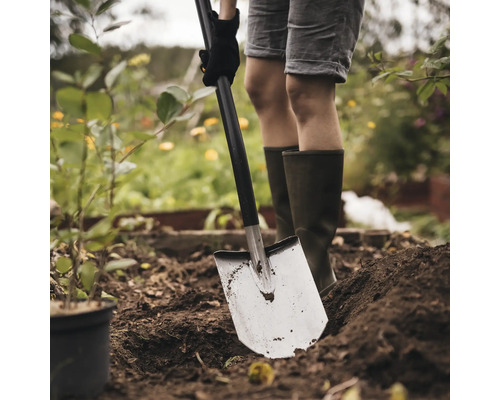 En person gräver i trädgården med en spade.