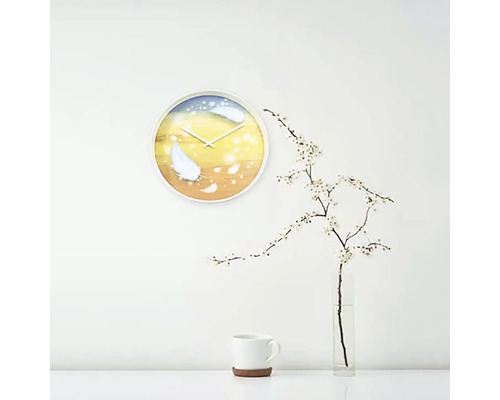 Väggklocka med fjädermotiv i ett ljust rum