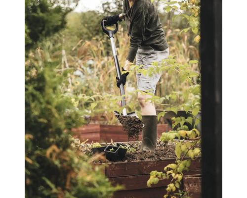 En person gräver med en spade i en trädgårdsbädd.