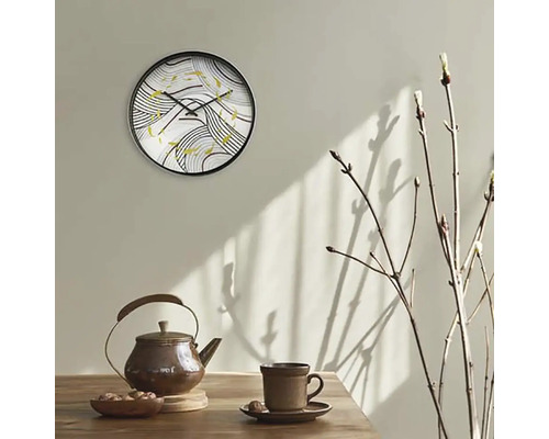Väggklocka med abstrakt mönster ovanför tekanna och kopp på bordet