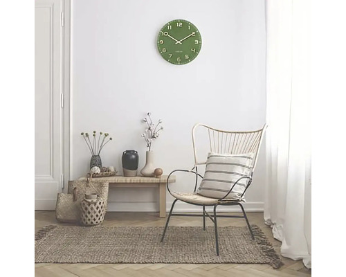 Vardagsrumsscen med grön väggklocka, fåtölj och matta
