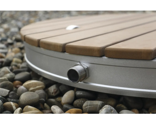 Detalj av en rund utomhusdusch med trägaller och vattenanslutning