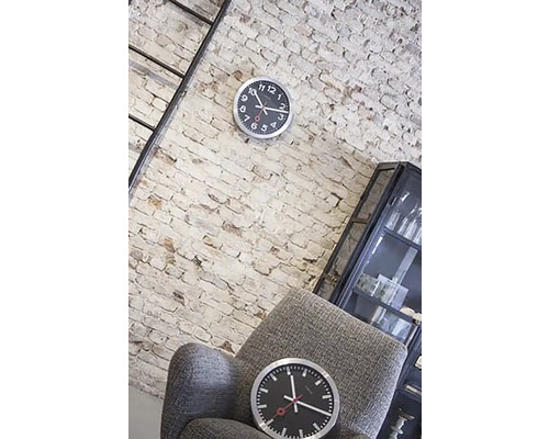 Vardagsrum med tegelvägg, stege, vitrinskåp, fåtölj och två klockor