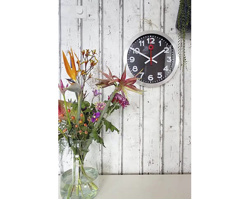 Väggklocka med blomvas på ett bord