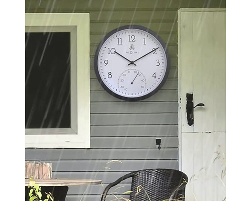 Utomhusbild av en väggklocka med termometer på en husvägg