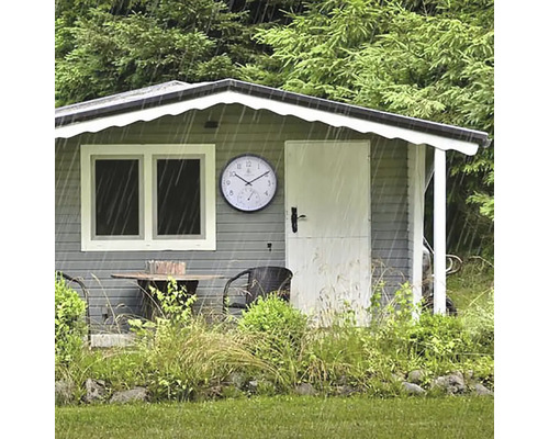 Trädgårdsscen med trädgårdshus, trädgårdsmöbler och en väderstation i regnet