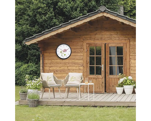Trädgårdshus i trä med väggklocka och sittgrupp på terrassen
