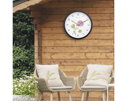 Trädgårdsscen med väggklocka på trävägg och två rottingfåtöljer med kuddar