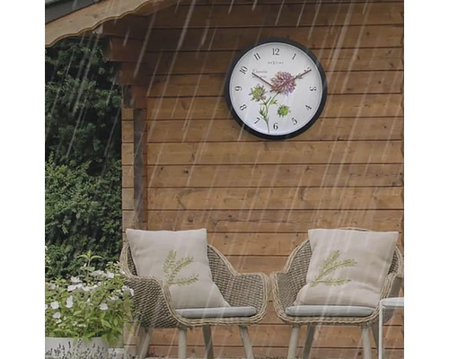 Trädgårdshus med utomhusklocka och två rottingfåtöljer med dynor