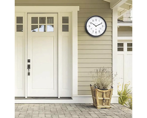 Scen med en utomhuskocka med termometer på en vägg bredvid en dörr och en blomlåda.