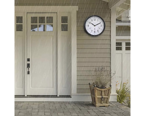 Scen med en rund, väderbeständig utomhusklocka bredvid en ytterdörr under ett regnskur.