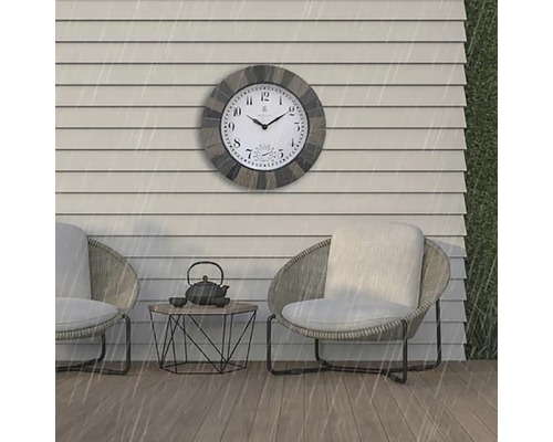 Utomhusscen med en väderbeständig väggklocka ovanför två stolar och ett litet bord