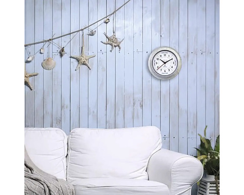 Dekorativt vardagsrum med väggklocka, soffa och maritim dekoration