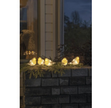 Dekorativa upplysta rödhakefigurer på en mur med grangrenar