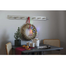 Dekorativt stilleben med bord, stolar, krans, ljusslinga och hatthylla