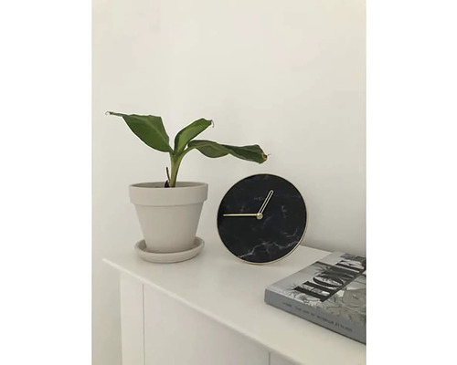 Bordsdekoration med krukväxt, rund klocka och bok