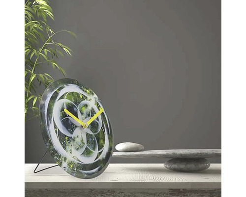 Bordsklocka med abstrakt blommönster och gula visare på ett bord