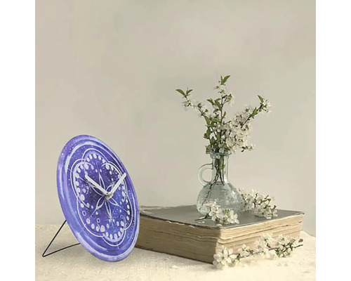 Bordsklocka med mönster bredvid blommor och bok