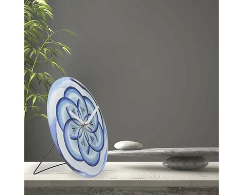 Dekorativ bordsklocka med blått blommönster på ett bord