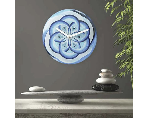 Väggklocka med blått blommönster bredvid stenbalans