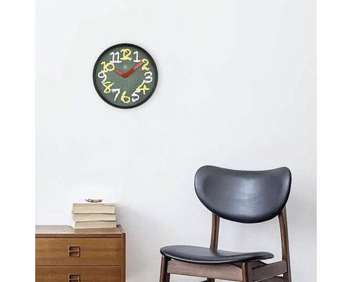 Väggklocka med urtavla och siffror ovanför ett träskåp och en stol