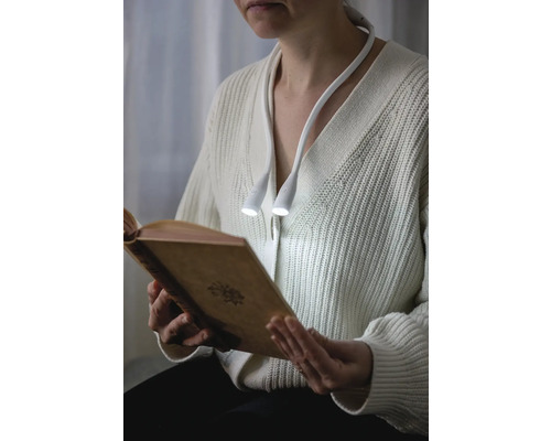 Kvinna läser bok med halslampa
