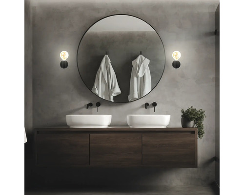 Modernt badrum med dubbla handfat, rund spegel och vägglampor