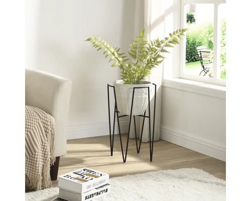 Rumsbild med växt i kruka på ett metallstativ.