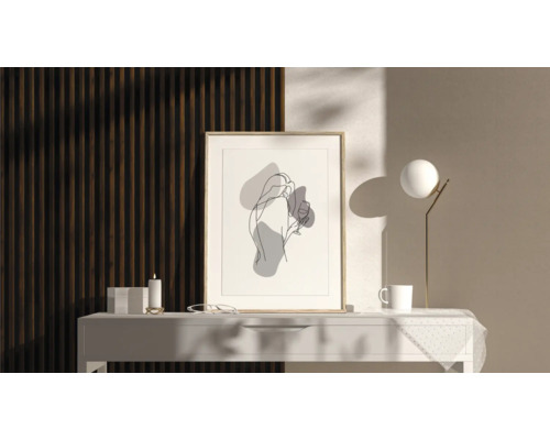 Dekorativ bild med abstrakt kvinnoillustration i ram på ett bord med lampa, kopp och ljus