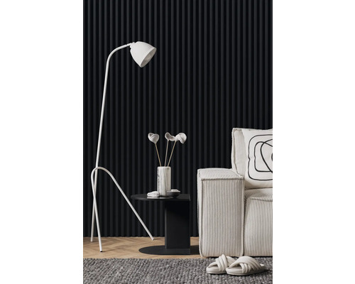 Vardagsrumsscen med golvlampa, sidobord, dekoration och fåtölj framför en vägg med paneler