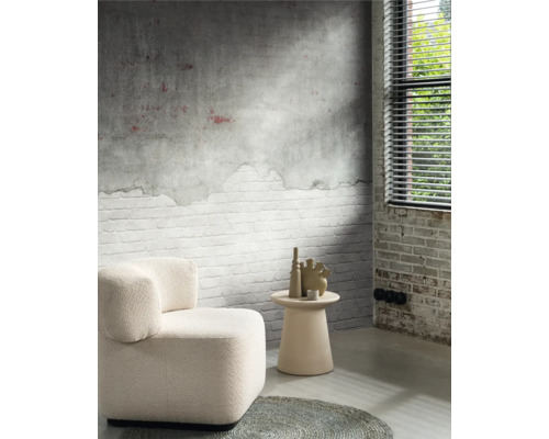 Vardagsrum med fåtölj, sidobord och dekorativa vaser framför en vägg med tegelmönster