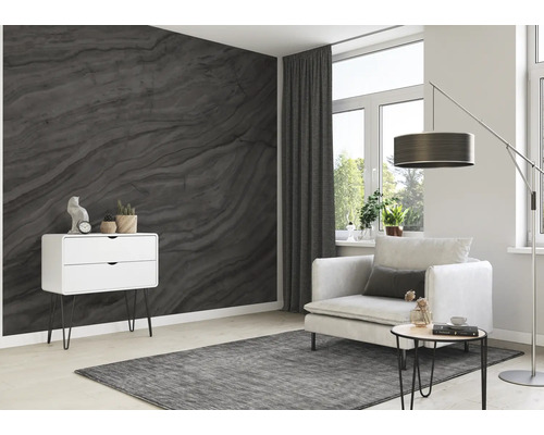 Vardagsrum med mönstrad tapet, fåtölj, matta och byrå