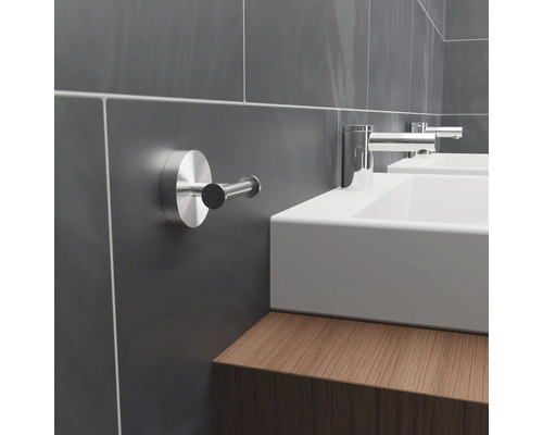 Modern badrum med grå kaklade väggar, handfat och handdukskrok.