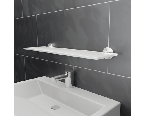 Vit vägghylla ovanför tvättställ i badrum