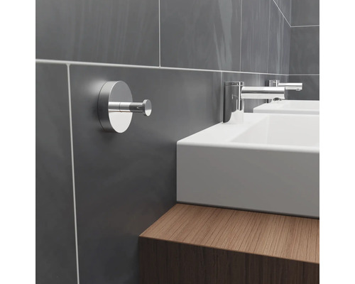 Detaljbild av ett badrum med en handdukshängare på väggen bredvid ett handfat