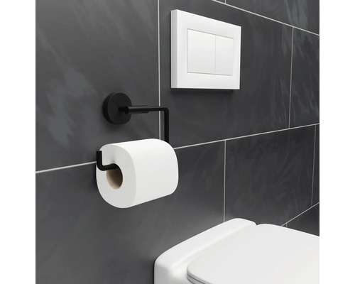 Toalettpappershållare i metall med toalettpappersrulle bredvid en toalettspolare