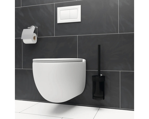 Modernt badrum med vägghängd toalett, toalettborste och toalettpappershållare