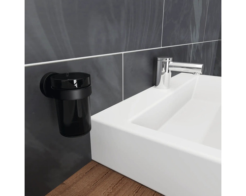 Svart tandborstmugg för väggmontering bredvid ett handfat