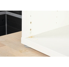 Detaljvy av en vit möbel med skruvar och träflis.