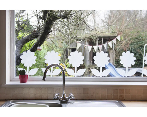 Fönsterdekoration med blommotiv, diskho och kran i förgrunden