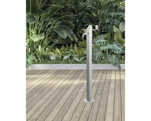 Trädgårdsdusch i metall med vattenkran framför växter