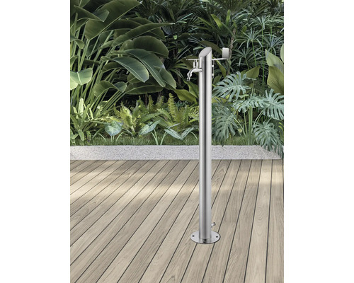 Trädgårdsdusch i rostfritt stål på trädäck framför frodig grönska