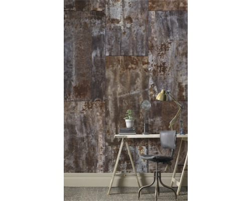 Ett arbetsrum med en vägg av paneler i rostutseende, ett skrivbord, en stol och en lampa.